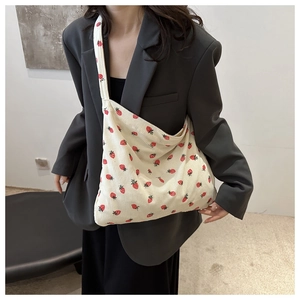 Detailed view of beige corduroy tote bag featuring red strawberry patterns and soft texture