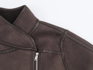 Detail of dark brown suede jacket featuring metal zipper and faux fur collar textures
