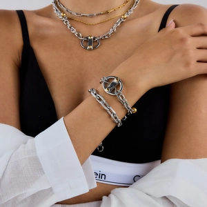 Détail du collier et bracelet multicouches en acier titane avec maillons et breloques dorées