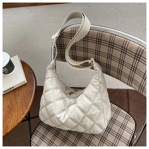 White quilted puffer crossbody bag hanging on a chair in a stylish cafe setting