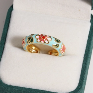 Macro view of blue enamel flower ring with golden edges in a green jewelry box