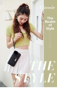 Close-up of black quilted clutch bag featuring fuzzy ball charm and golden metal hardware