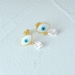 Macro detail of silver evil eye earrings with blue enamel and crystal drop pendants