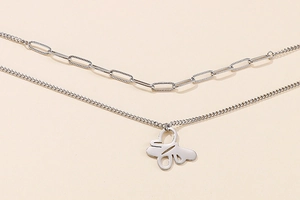 Close-up of a silver double-layered necklace featuring a hollow butterfly pendant