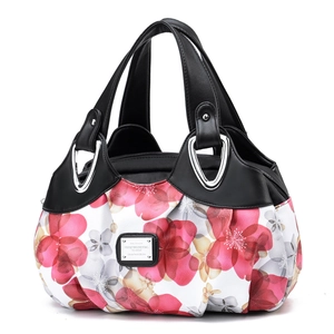 Detail of red floral print nylon handbag with black leather handles and silver metal rings