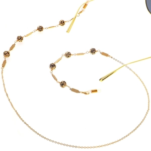 Close-up of golden eyeglasses chain with black beaded accents on a clean white background