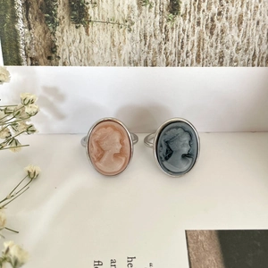 Detail of vintage cameo rings with female profile in peach and blue on marble background