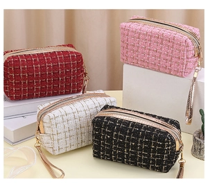 Detailansicht rechteckiger Tweed-Kulturtaschen in Rot, Rosa, Weiß und Schwarz mit Gold-Reißverschluss