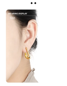 Close-up of a model wearing gold triangular earrings with micro-inlaid zircon stones