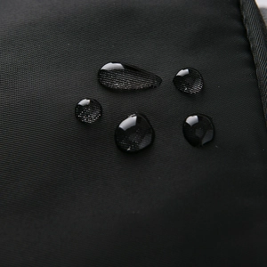 Macro shot of waterproof high-density nylon fabric with water droplets on black surface