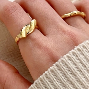 Close-up of dual-style gold knotted and wavy silver rings worn on a model hand