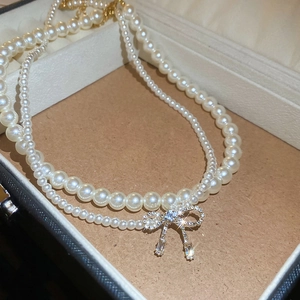 Close-up of double-layer pearl necklace featuring a zircon-studded bow pendant in a gift box