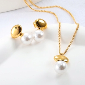 Elegant gold oval necklace and pearl stud earrings jewelry set on a ceramic tray