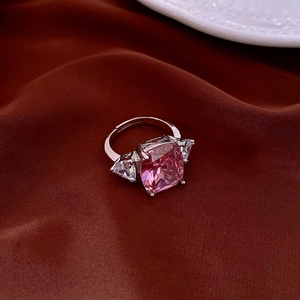 Macro detail of rectangle pink zircon ring with triangle side stones on red silk