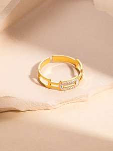 Detailed view of hollow geometric gold ring with cubic zirconia on stone background