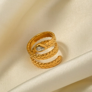 Detailed view of a gold snake ring with teardrop zircon on champagne silk fabric