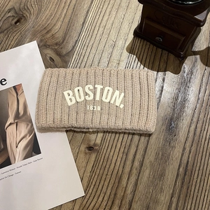 Détail d'un bandeau en maille beige avec broderie Boston 1630 sur table en bois
