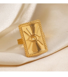 Détail d'une bague œil maléfique dorée avec gravure sur du satin crème doux