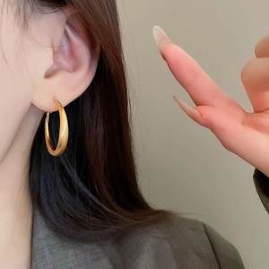 Close-up of matte gold large hoop earrings worn by a model for elegant metal texture