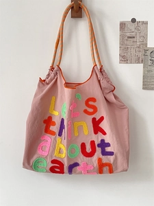 Detail of pink canvas tote bag featuring 3D 'Earth' embroidery and rope handles