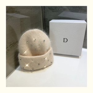 Detailed close-up of cream knit beanie featuring sparkling rhinestones on soft fabric