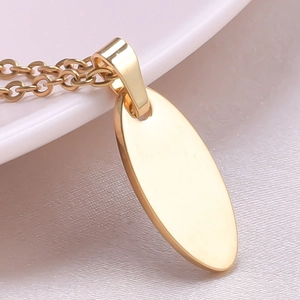 Close-up of a polished golden oval pendant necklace with a 18k mirror finish on white ceramic