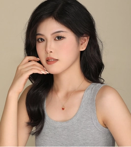 Detail of red agate heart pendant necklace on model with golden chain and sleek finish