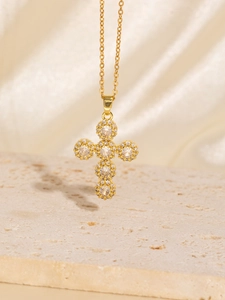 Detailed view of a gold cross pendant necklace inlaid with sparkling cubic zirconia