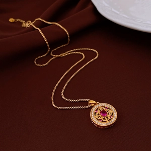 Detailed view of vintage gold cross necklace with a red stone on silk background