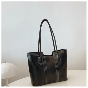 Detail of black tote bag featuring white contrast stitching and long shoulder handles