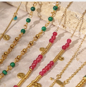 Detail of handmade beaded gold chain necklaces with colorful stones and hammered pendants