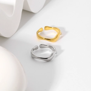 Dettaglio di anelli minimalisti oro e argento con linee fluide e forma irregolare