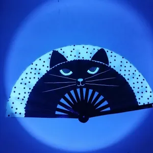 Detail of folding fan showing black cat face with glowing eyes and black polka dots