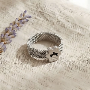 Detailed close-up of silver mesh band ring with pet paw and bone motif on linen background