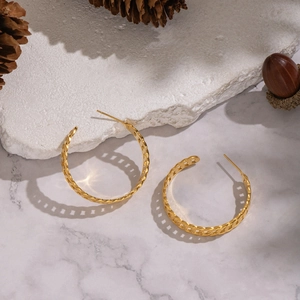 Boucles d'oreilles créoles dorées géométriques évidées sur présentoir en pierre
