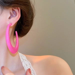 Side view of large pink geometric C-shaped hoop earrings on model with glossy finish