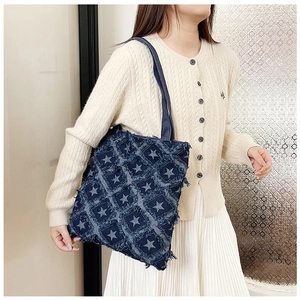 Detail of blue denim tote bag with star patterns and distressed edges for casual style