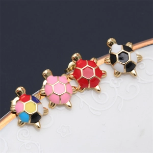 Close-up of cute colorful enamel turtle stud earrings on a vintage white plate