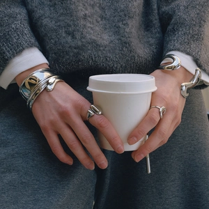 Detail of silver fluid metal bracelets and rings with mirror finish on a model