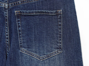 Dettaglio ravvicinato delle cuciture e della trama denim della tasca dei jeans blu scuro