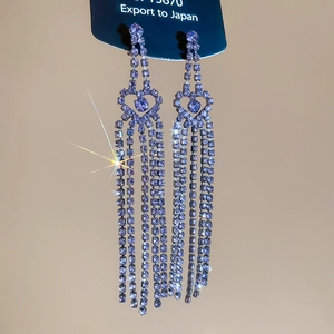 Detail of silver needle earrings with purple crystal hearts and long tassel fringes