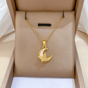 Macro shot of gold crescent moon and butterfly pendant with inlaid zircon and shell
