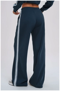 Detail view of navy blue jogger pants with white side stripes shown on model from behind