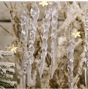 Close-up of clear spiral icicle ornaments hanging on a snowy Christmas tree branch