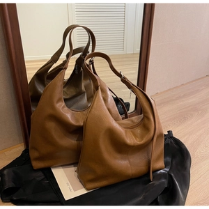 Detailed view of a brown leather hobo bag reflecting in a mirror showing side texture