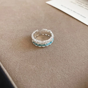 Detailed macro view of silver flower ring with blue enamel and sparkling zircons