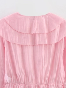 Détail du dos d'un chemisier rose à volants avec texture plissée et taille élastique