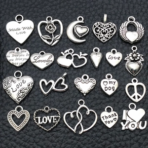 Detailed view of silver heart charms in various designs on black textured surface