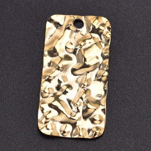Macro shot of rectangular gold-plated stainless steel pendant with textured hammered surface