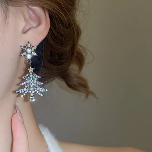 Close-up of snowflake and pearl Christmas tree earring with colorful rhinestones on ear